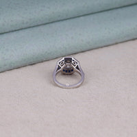 Silver ring with gemstone on a light gray surface,  round CZ halo ring, retro art deco ring, sapphire wedding ring, vintage-style sapphire ring, fancy cut CZ ring, antique-inspired ring