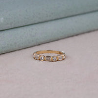 Gold ring with diamonds on a light background, Elegant Emerald & Round Moissanite Ring – Seven Stone Bezel Half Eternity Band