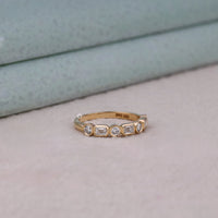 Gold ring with embedded diamonds on a neutral background, Bezel Setting Emerald & Round Moissanite Band – Seven Stone Half Eternity Wedding Ring