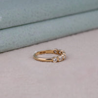 Rose gold ring with three diamonds on a neutral background, Modern Bezel Set Moissanite Band – Emerald & Round Seven Stone Eternity Ring