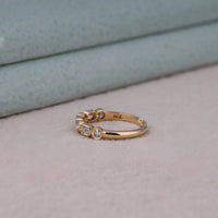 Gold ring with embedded diamonds on a neutral background, Half Eternity Emerald & Round Moissanite Band – Bezel Set Seven Stone Ring for Women