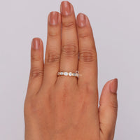 Hand wearing a diamond ring on a plain background, Half Eternity Bezel Set Ring – Emerald & Round Moissanite Seven Stone Wedding Band