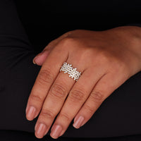 Hand wearing a silver ring with small diamonds on a black background