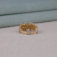 Gold ring with floral design on a light gray surface