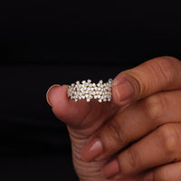 Hand holding a diamond ring against a black background