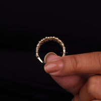 Gold ring with small stones held between fingers against a black background
