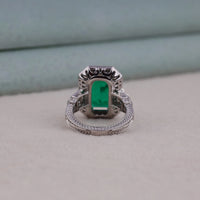 Silver ring with a green gemstone on a light gray background