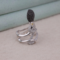 Silver octopus-shaped ring with black and clear gemstones on a light background, Underwater Inspired Octopus Statement Ring, Black & White CZ with Yellow Eye Detail