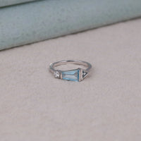Silver ring with a blue gemstone on a beige surface, Aquamarine and CZ Three Stone Minimalist Ring, Elegant Baguette, Round & Triangle Setting