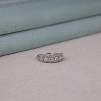 Silver ring with diamonds on a light gray surface, Seven Stone Round Moissanite Engagement Ring – White Gold Halo Design for Her