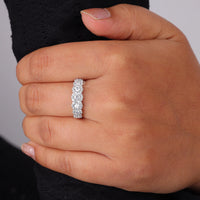 Close-up of a hand wearing a diamond ring on a neutral background, Seven Stone Halo Moissanite Engagement Ring – Sparkling Round Cut Bridal Ring