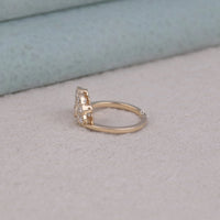 Rose gold ring with diamonds on a light gray surface, Art Deco Inspired Edwardian Moissanite Ring