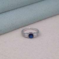 Silver ring with a blue gemstone on a light gray surface, Three Stone Art Deco Ring, Vintage Style Engagement Ring