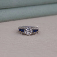 Silver ring with blue gemstones on a beige surface