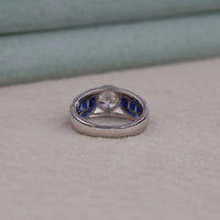 Silver ring with blue gemstone on a beige surface