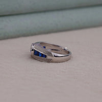 Silver ring with blue gemstones on a beige surface
