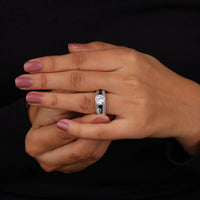Close-up of a hand wearing a diamond ring on a black background
