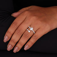 Hand wearing a silver ring with a diamond on a black background