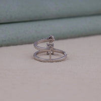 Silver ring with a small diamond on a light gray surface