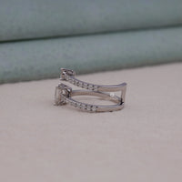 Silver ring with small diamonds on a light gray surface