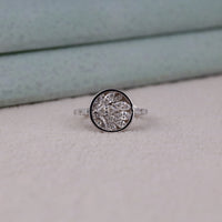 Silver ring with a diamond cluster on a light gray surface