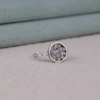 Silver ring with embedded diamonds on a light gray surface