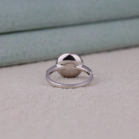 Silver ring with a unique design on a light gray surface
