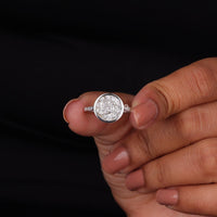 Silver ring with a diamond on a finger against a black background
