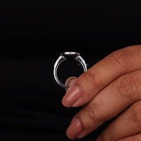 Silver ring held by a hand against a black background