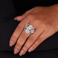 Close-up of a hand wearing a silver ring with floral design on a black background
