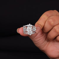 Hand holding a silver ring with floral design against a black background