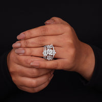Hand wearing a silver floral ring on a black background