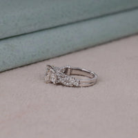 Silver ring with gemstones on a light surface, Classic Princess Cut Moissanite Engagement Ring – Vintage Detailed Bridal Band