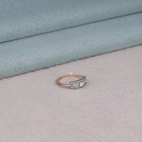 Diamond ring on a light gray surface with a textured blue background, east west moissanite ring, oval moissanite engagement ring, baguette moissanite ring, knife edge band ring, modern moissanite ring