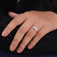 Close-up of a hand wearing a silver ring with a diamond on a dark background, East West Oval Moissanite Ring with Baguette Side Stones – Knife Edge Modern Engagement Ring