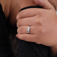 Close-up of a hand wearing a silver ring with a black background, Knife Edge Moissanite Engagement Ring – Oval East-West Set with Baguette