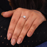 Hand wearing a silver ring with a diamond on a dark background, “Heart Shape Moissanite Solitaire Ring, Minimalist Engagement & Valentine’s Gift Jewelry”
