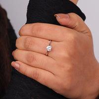 Hand wearing a diamond ring on a neutral background, “Minimalist Heart Cut Moissanite Engagement Ring, Dainty Promise & Valentine’s Gift”