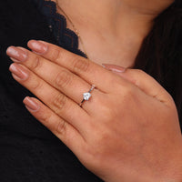 Hand wearing a diamond ring with a blurred background, “Heart Cut Moissanite Minimalist Solitaire Ring, Dainty Engagement Ring & Valentine’s Day Gift”