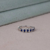 Silver ring with blue gemstones on a neutral background, Blue Sapphire & White CZ Wedding Band – Round Cut Alternative Eternity Ring