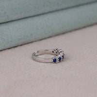 Silver ring with blue gemstones on a light gray surface, Round Blue & White Sapphire CZ Ring – Alternative Bridal Band