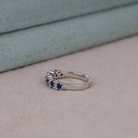 Silver ring with blue gemstones on a neutral background, Unique Blue and White CZ Sapphire Band – Round Stone Alternative Wedding Jewelry