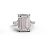 Diamond ring with emerald-cut center stone on a white background