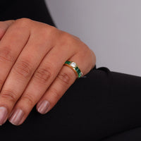 Gold ring with green gemstones on a person's finger against a gray background, Bezel and Channel Set CZ Ring, Round & Green Emerald Baguette Statement Jewelry