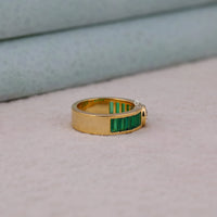 Gold ring with green gemstones on a light gray surface, Round and Emerald Baguette CZ Stone Ring, Classic Bezel & Channel Setting Band, Elegant Cubic Zirconia Wedding Anniversary Ring