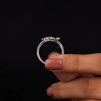 Silver ring held between fingers against a black background