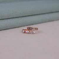 Rose gold ring with diamonds on a light gray surface, Contemporary Moissanite Bypass Ring – Pear and Baguette Channel Set Design