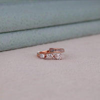 Rose gold ring with heart-shaped gemstones on a light gray surface, Pear Cut Moissanite Open Ring – Channel Set Baguette Bypass Statement Jewelry
