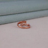 Rose gold ring with a unique design on a light gray surface, Pear with Baguette Moissanite Channel Set Ring – Open Bypass Modern Jewelry