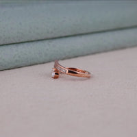 Rose gold ring with small diamond on a light gray surface, Rose Gold Moissanite Bypass Ring – Pear & Baguette Channel Set Open Gap Design